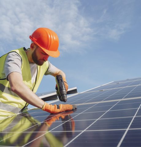 Male worker with solar batteries. Man in a protective helmet. Installing stand-alone solar panel system.